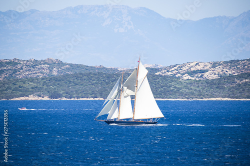 Stunning view of a beautiful sailboat sailing on the Mediterranean sea that bathes the coasts of Sardinia. Maddalena Archipelago National Park in the background, Sardinia, Italy.