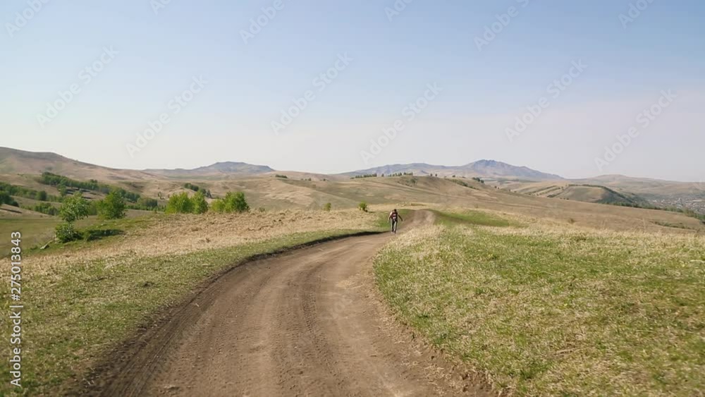 man with beard mustache with a tattoo his arm with red backpack, a parachute. walking along country road near the mountains. in a striped yellow-white t-shirt and jeans. blur man with beard mustache with a tattoo his arm with red backpack, a parachute. walking along country road near the mountains. in a striped yellow-white t-shirt and jeans. blur