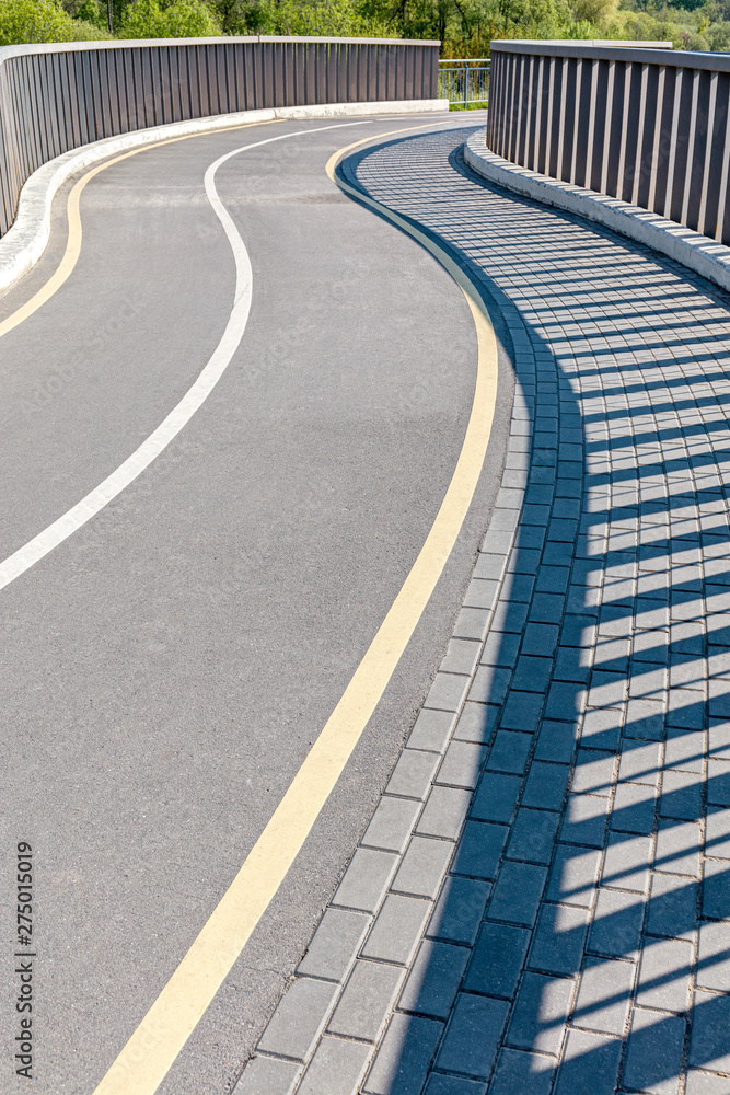 Fototapeta premium pedestrian bridge in city park with bicycle lane in S shape