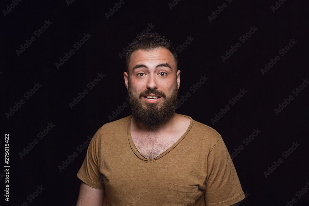 Close up portrait of young man isolated on black studio background. Photoshot of real emotions of male model. Wondering, exciting and astonished. Facial expression, human emotions concept.