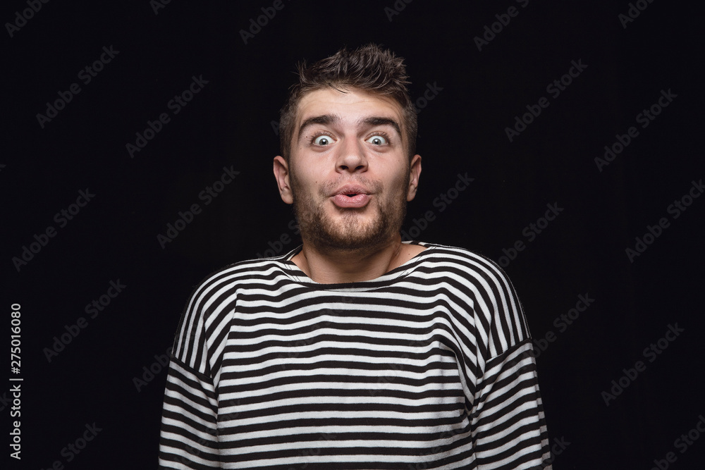 Close up portrait of young man isolated on black studio background. Photoshot of real emotions of male model. Wondering, exciting and astonished. Facial expression, human emotions concept. Close up portrait of young man isolated on black studio background. Photoshot of real emotions of male model. Wondering, exciting and astonished. Facial expression, human emotions concept.