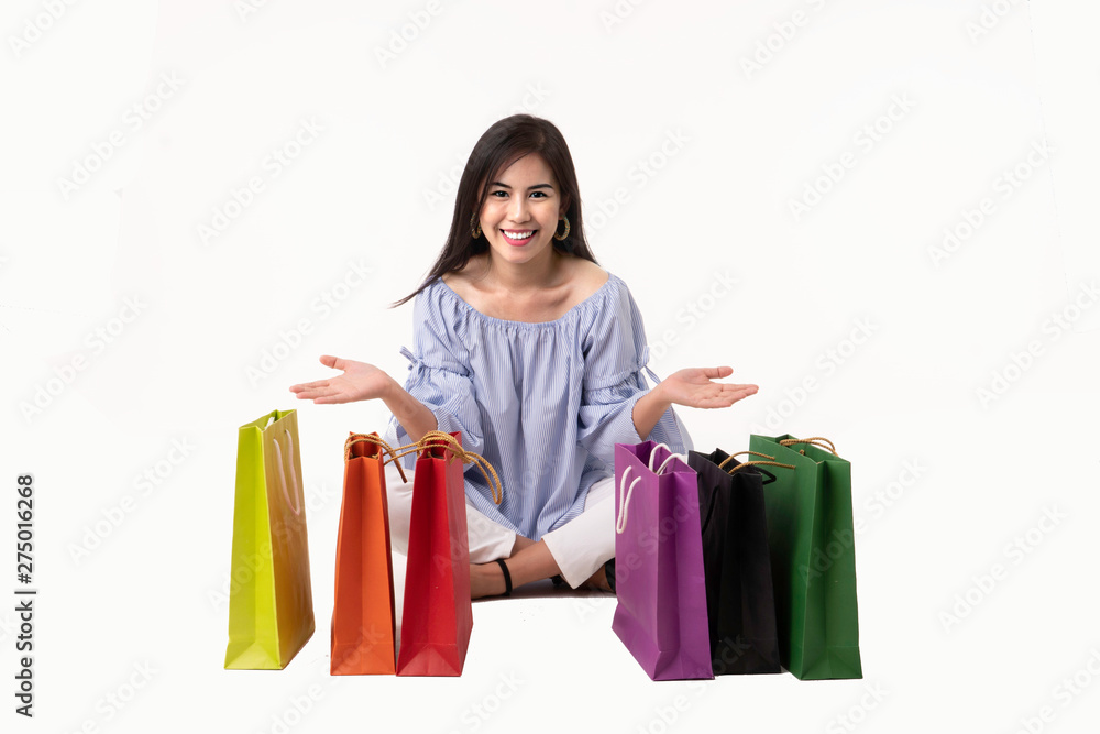 Happy Asian young woman sitting with shopping bags isolated on white background