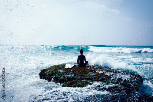 Woman practice yoga at the seaside coral cliff edge face the waves