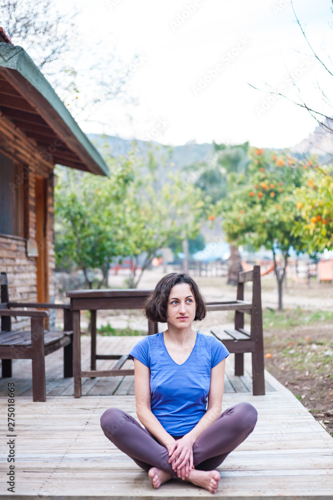 A woman is sitting on the porch of an old wooden house.