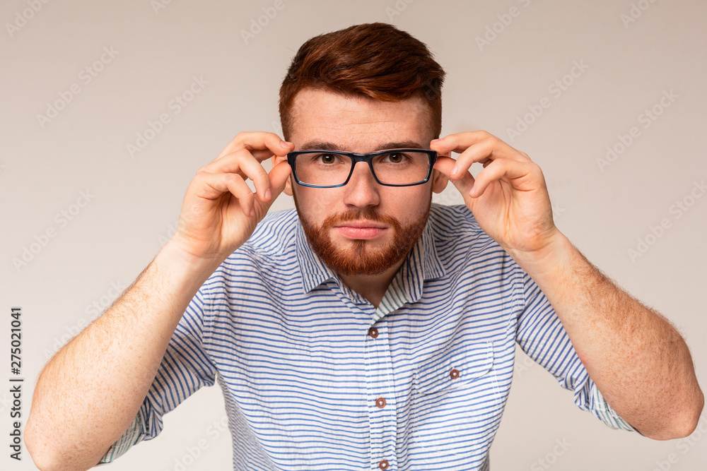 Young redhaired guy try on glasses in front of camera Young redhaired guy try on glasses in front of camera