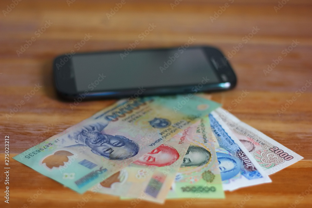 Dong, Vietnam money on wood table with smartphone . Dong, Vietnam money on wood table with smartphone .