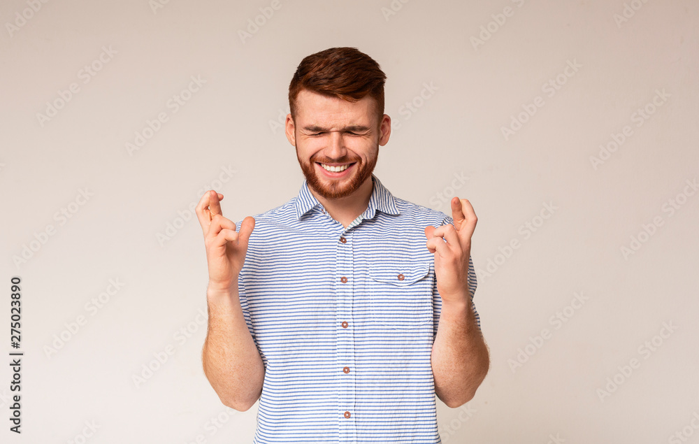 Young guy with closed eyes hopes for fortune and good luck Young guy with closed eyes hopes for fortune and good luck