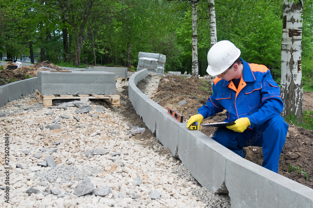 a control worker makes a measurement of the quality of the road construction course
