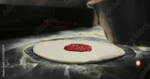 tomaoto sauce spooned and spread over pizza dough. Authentic Neapolitan Pizza cooked in a wood fire oven.