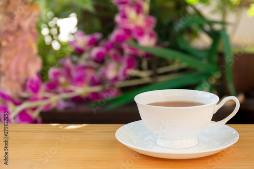 Cup of tea on wooden table in garden with blur background.