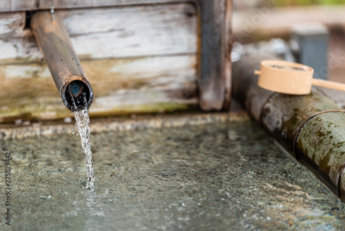 Purification fountain in Kyoto, Japan with wooden bamboo ladle and water running from spout
