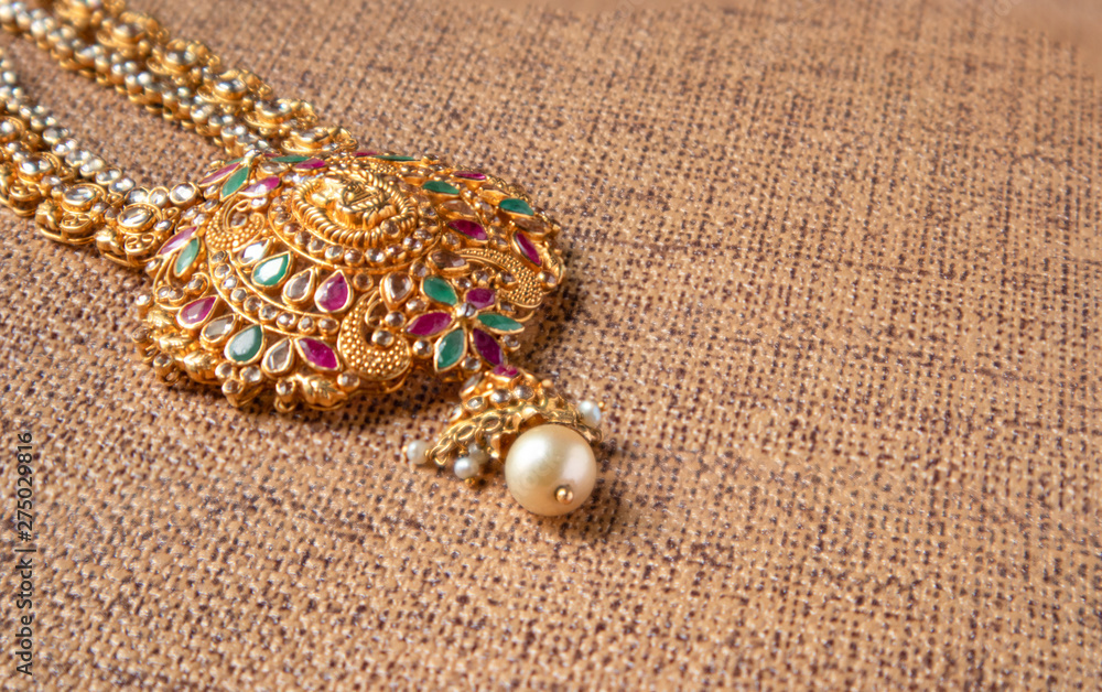 Gold Guttapusalu Necklace with gemstones a traditional Indian wedding jewelry on wooden textured background. Gold Guttapusalu Necklace with gemstones a traditional Indian wedding jewelry on wooden textured background.