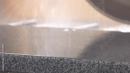 Drops of water fall on the polished slab. Granite processing in manufacturing. Cutting granite slab with a circular saw.  Wet granite saw, cutting moment. photo