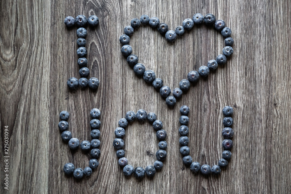 Ripe tasty blueberries and berries on a wooden table with I love you words