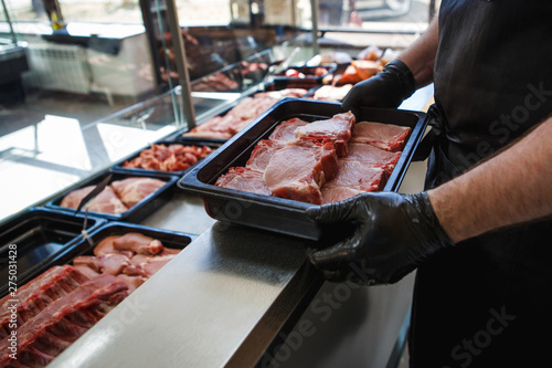 Raw meat in trays in the window of a butcher shop. The seller puts the meat on display in black trays
