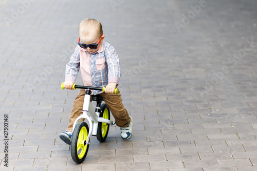 Fototapeta Naklejka Na Ścianę i Meble -  Little cute boy learns to balance on a bike in the park. Active leisure