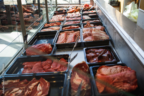 Raw meat in trays in the window of a butcher shop. The seller puts the meat on display in black trays