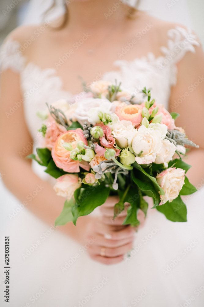 Bride in a wedding dress holding a wedding bouquet in her hands close-up Bride in a wedding dress holding a wedding bouquet in her hands close-up