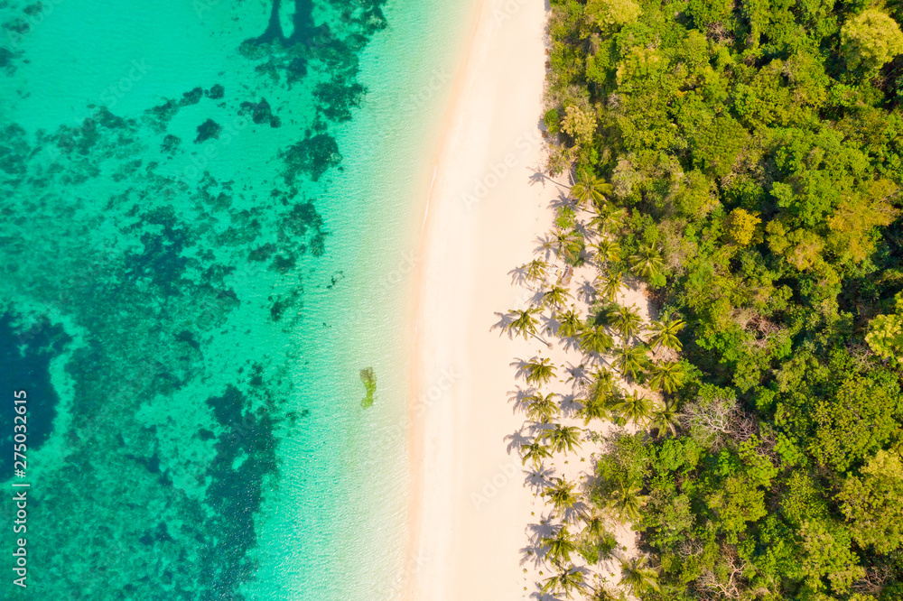 Turquoise lagoon with a coral reef and white beach. Beach with white sand and palm trees, view from above. Puka Shell Beach, Boracay Island, Philippines, aerial view.