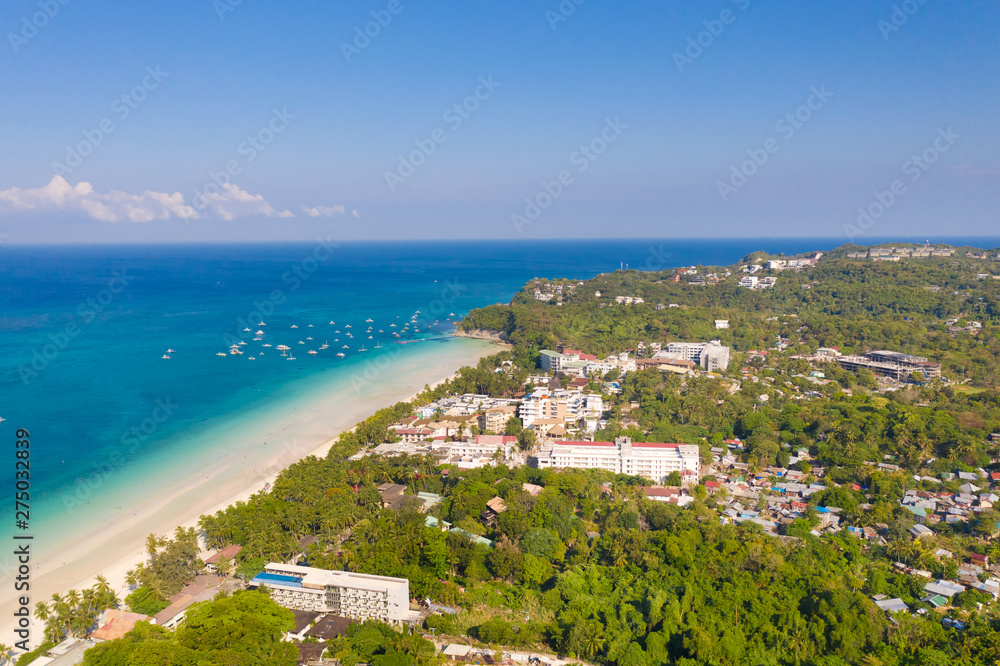 Island Boracay, Philippines, view from above. White beach with palm trees and turquoise lagoon with boats. Buildings and hotels on the big island.