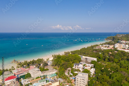 Island Boracay, Philippines, view from above. White beach with palm trees and turquoise lagoon with boats. Buildings and hotels on the big island.