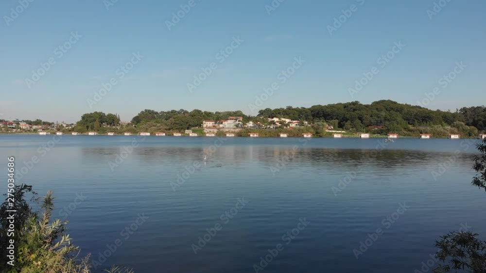 Pedestal aerial shot take off above lake and village Pedestal aerial shot take off above lake and village