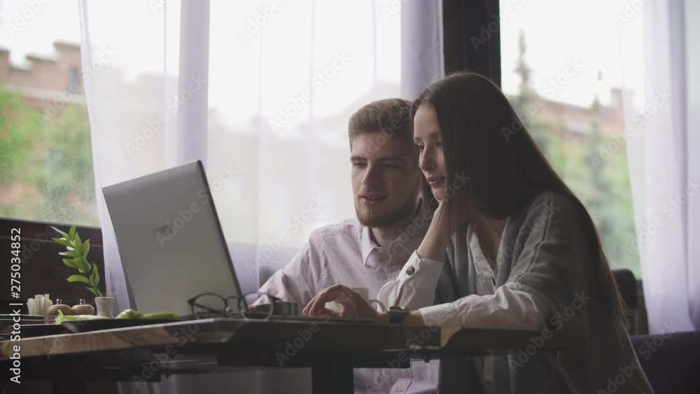 Young couple is working in cafe on laptop and smiling Young couple is working in cafe on laptop and smiling