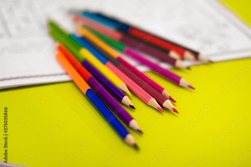colored pencils on yellow table beside drawing album colored pencils on yellow table beside drawing album