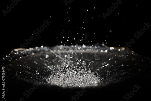 The splash of water drops in loudspeaker on black background. Perpetual motion, music and power concept.