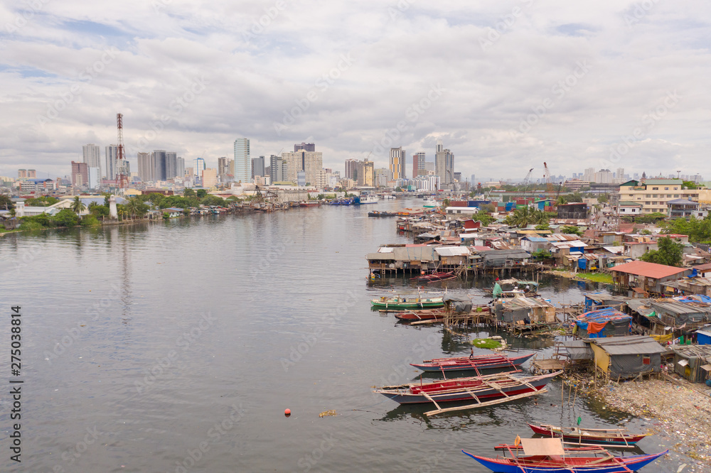 Manila slums on the background of a big city. Houses and boats of the poor inhabitants of Manila. Dwelling poor in the Philippines. Contrast social strata.