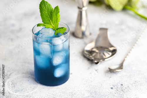 Blue lagoon, Tropical cocktail served with ice cubes decorated with mint. Refreshing alcohol drink for party at summer.
