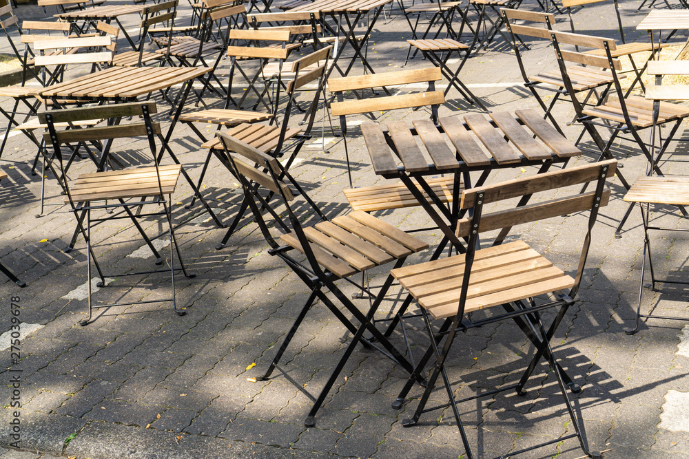Before the party begins: empty wooden tables and chairs in the sunshine Before the party begins: empty wooden tables and chairs in the sunshine