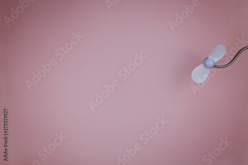 Small white plastic fan on a pink background. Place for text
