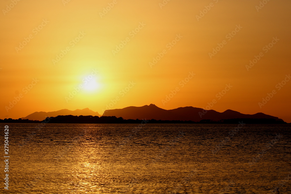 evocative image of the sunset over the sea with a promontory in the background in Sicily