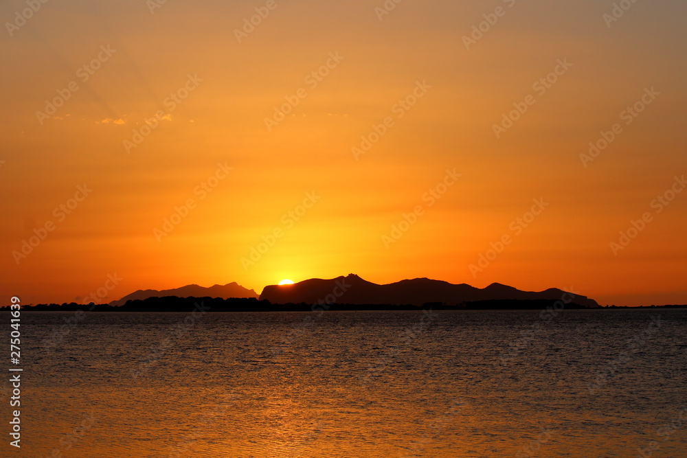 evocative image of the sunset over the sea with a promontory in the background in Sicily