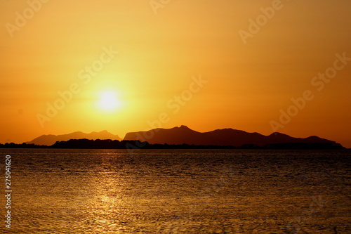 evocative image of the sunset over the sea with a promontory in the background in Sicily © massimo