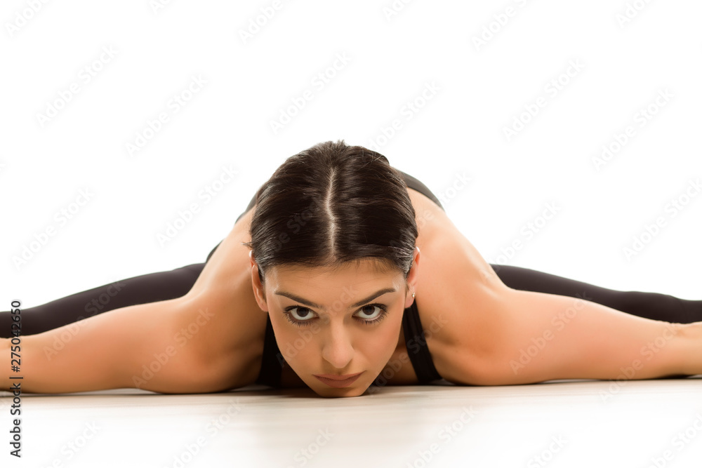 Fototapeta premium Flexible young woman doing yoga side leg and arms splits on white background 