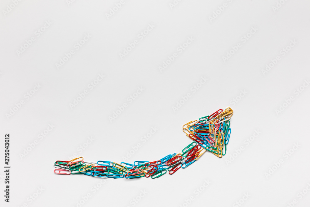 An arrow made from paperclips pointing upwards on a white background, shot from above. An arrow made from paperclips pointing upwards on a white background, shot from above.