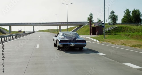 TRACKING Old classic vintage 70s muscle car driving thorough rural landscape. 4K UHD RAW graded footage