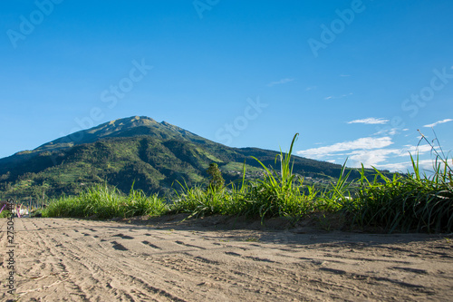 Dirt road leading towards a mountain in rural Indonesian farming village