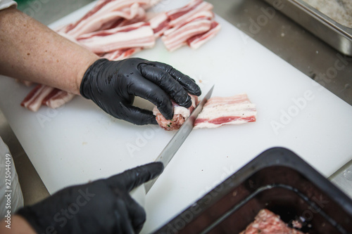 The process of preparing meat products. Gloved hands are molded from ground beef and bacon patties