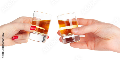 Two hands clinking shots of alcoholic beverage together