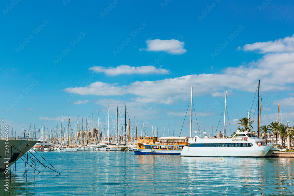tourist ships and small sailing boats in the safe harbor city of Palma de Mallorca against the blue sky