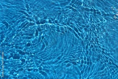 Blue and bright water surface with sun refection in swimming pool for background