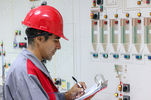 Engineer Writing on Clipboard in Chemical Plant Control Room