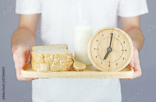 Man with white T Shirt holding breakfast (Bread and milk bottle) serve in wooden plate photo