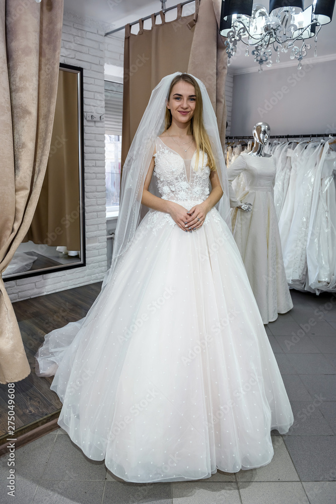 Fototapeta premium Beautiful bride in salon posing in wedding dress