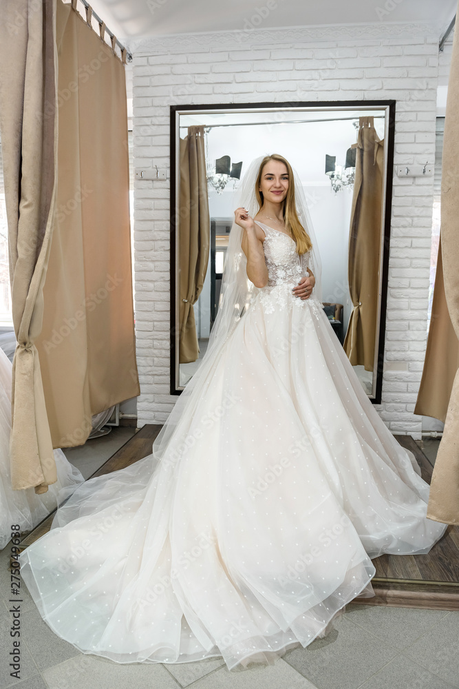 Happy bride in wedding dress standing in salon Happy bride in wedding dress standing in salon