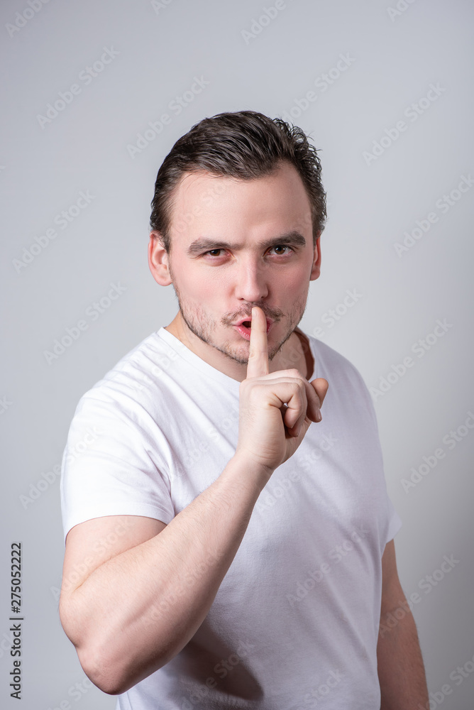 Handsome guy with bristles in a white T-shirt makes funny grimaces on his face Handsome guy with bristles in a white T-shirt makes funny grimaces on his face