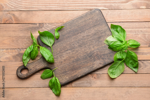 Wooden board with fresh basil on table